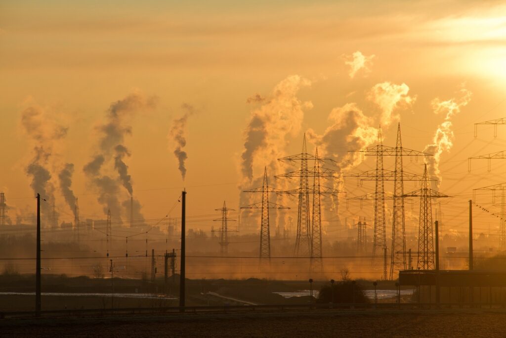 Smoke rises from power station chimneys in a hazy orange sky